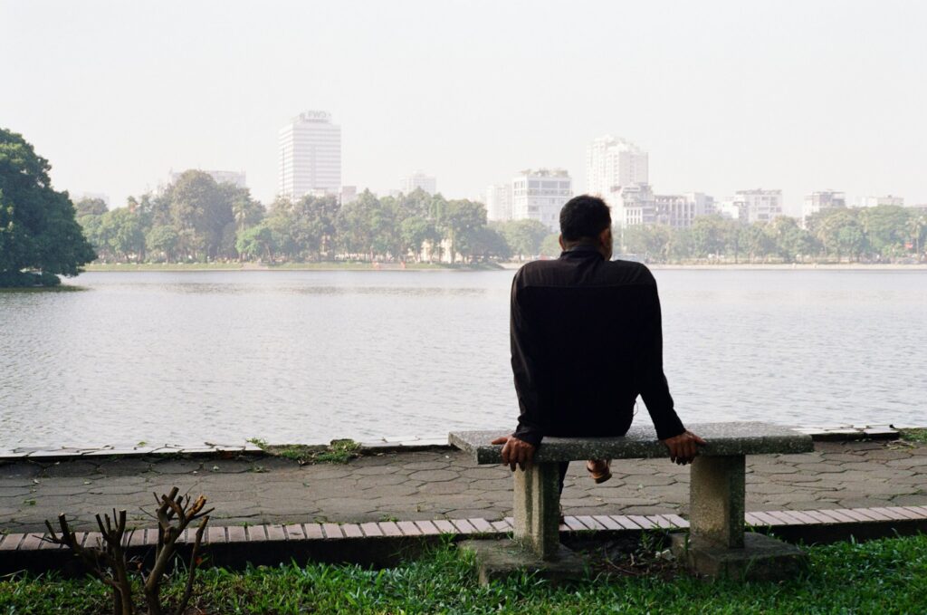 Man sitting on bench overlooking a lake and city